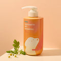 Orange pump bottle of INOOM Our Earth Pet Shampoo beside chamomile flowers