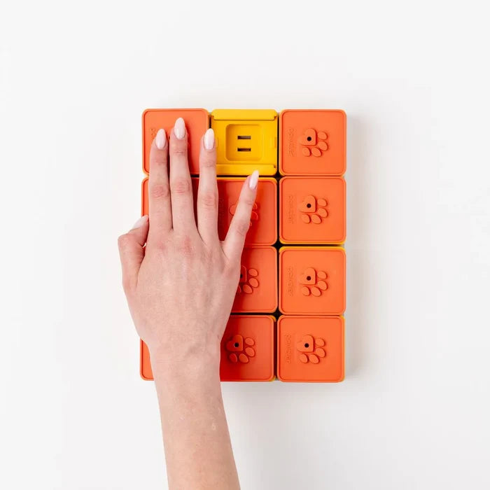 Hand sliding a tile on the Pawzler Treat Maze interactive dog puzzle