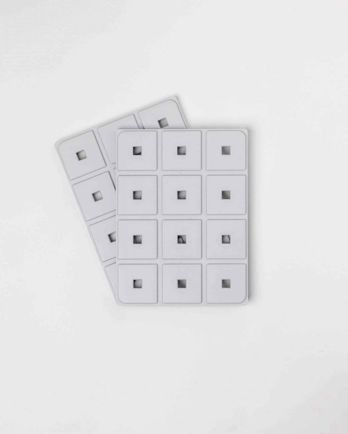 Two white Pawzler Base Pawzle trays with hidden square compartments, overhead view