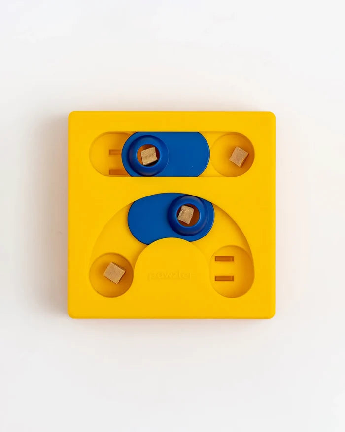 Yellow Pawzler Kaya puzzle piece with sliding blue covers over treat holes, treats visible inside