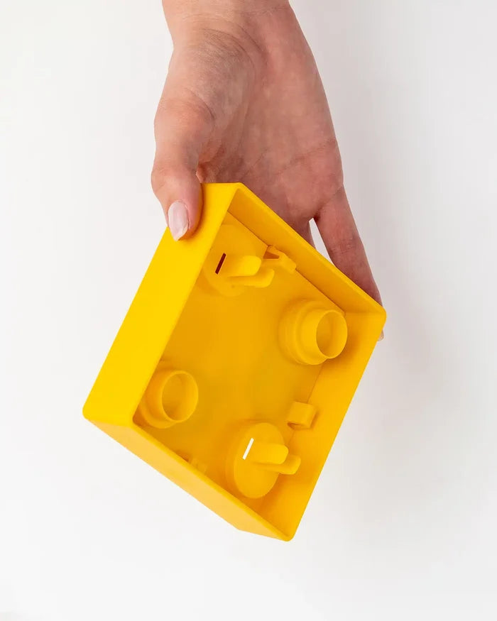 Hand holding an upside-down yellow Pawzler Kaya puzzle piece showing its connector pegs underneath