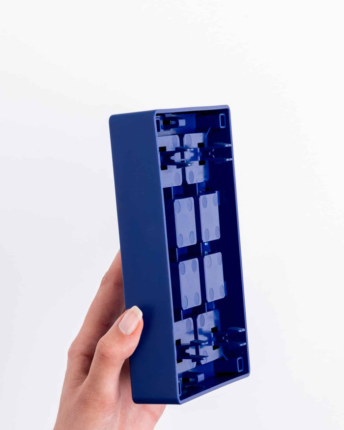 Hand holding the navy blue Pawzler Louvre puzzle tray, showing its hollow underside