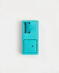 Closed teal Pawzler Nai puzzle piece with sliding door and bone-icon door, top-down view