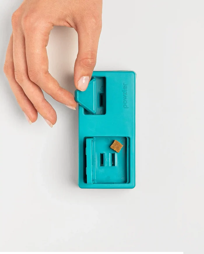 Hand lifting the sliding door on the teal Pawzler Nai puzzle piece