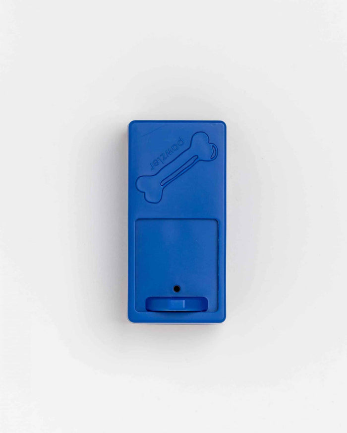 Closed blue Pawzler Onix puzzle piece with bone icon and sliding treat drawer, top-down view