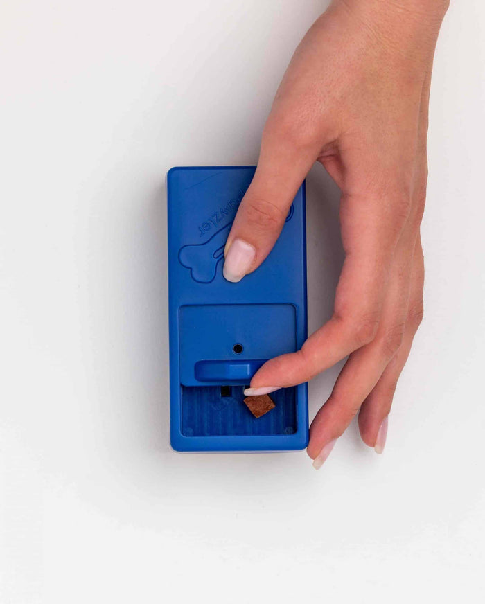 Hand pulling a treat from the sliding drawer on the blue Pawzler Onix piece