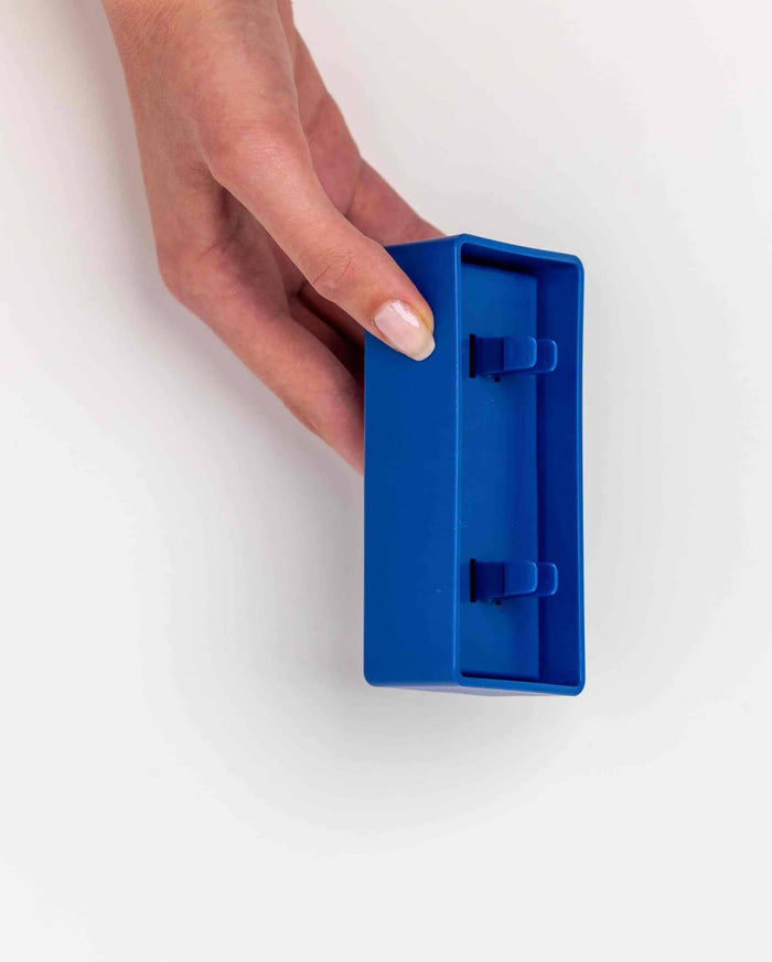 Hand holding the blue Pawzler Onix puzzle piece, showing its underside attachment clips