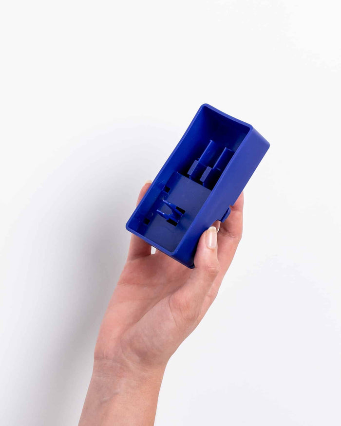 Hand holding the navy blue Pawzler Sela puzzle piece, showing its underside attachment