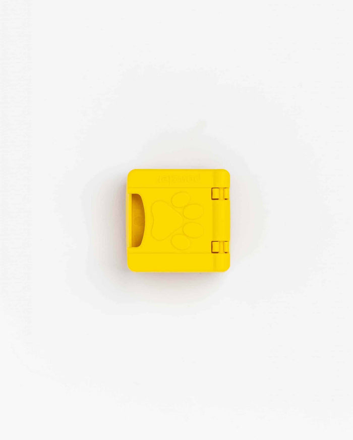 Closed yellow Pawzler Zoey puzzle piece with a paw-print cut-out, top-down view