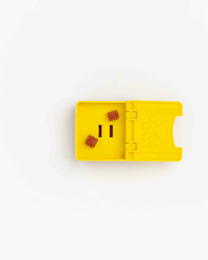 Open yellow Pawzler Zoey puzzle piece with treats inside its compartment