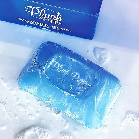 Sudsy Plush Puppy Wonder Blok soap bar beside its box in a bath