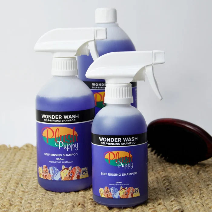 Three Plush Puppy Wonder Wash self-rinsing shampoo spray bottles grouped together with a grooming brush