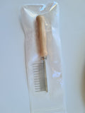 Wooden-handled shedding comb with fine metal teeth in its packaging