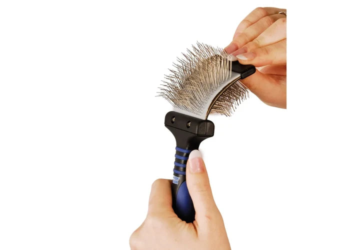 Hand pressing down on the flexible wire pins of the Show Tech Twin Flex Slicker to show their spring action