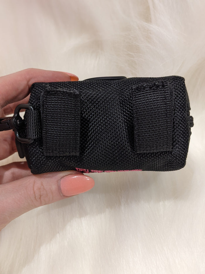Hand holding the black Spitz Groom poo bag holder, showing its velcro straps on the back