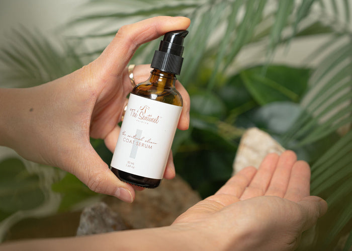 Hands pumping The Sentinel Coat Serum from its amber bottle into an open palm